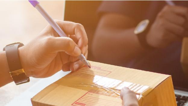 Customer signing for a parcel that is being delivered. 