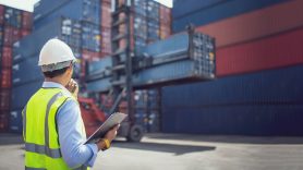 man with clipboard looking at containers