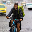 man delivering parcel on his bike in the rain