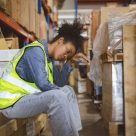 girl in high vis jacket sitting in the warehouse