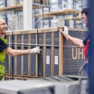 wrapped dhl parcel being pushed out of a warehouse by man 