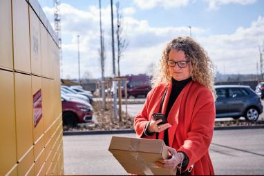 Woman scans her parcel in front of a Parcel Locker