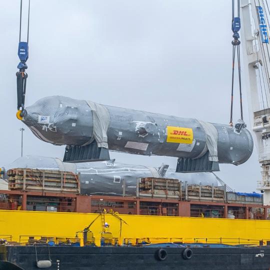 "Twee DHL Industrial Projects hijsen een olietank op een schip."