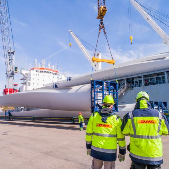 Dos operarios de DHL Industrial Projects supervisan el traslado de un molino de viento