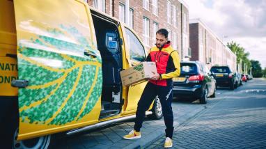 DHL electric van with a DHL driver holding a parcel ready for delivery