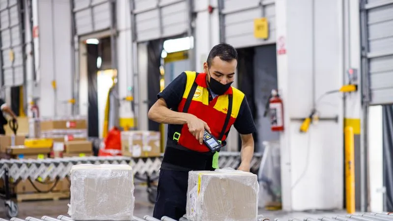 DHL Express employee checking a box of linen shipped from Pakistan to the UK