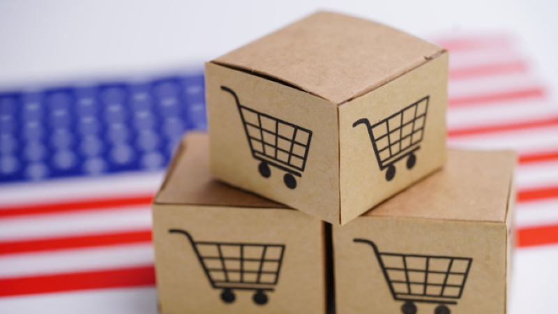 close-up of a boxes with a shopping cart logo with an american flag in the background