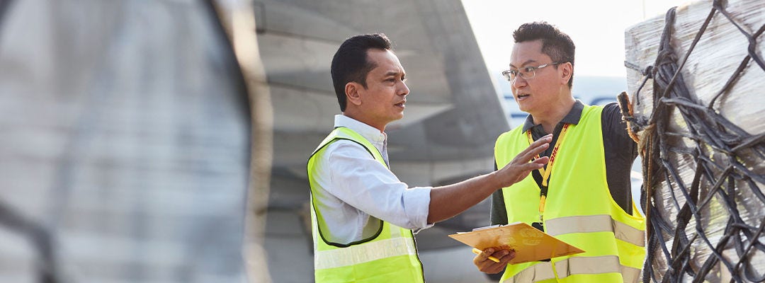 two men talking on an airport tarmac