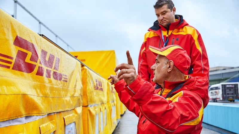 two dhl employees standing in front of freight boxes