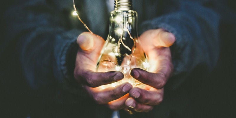 Hands holding an illuminated bulb