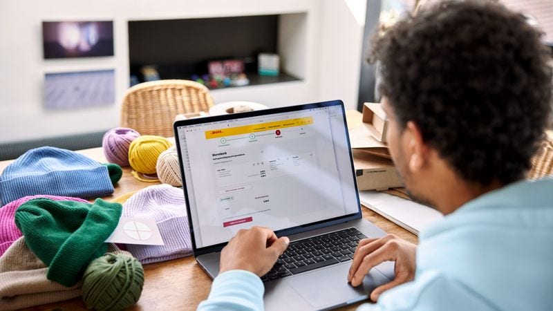 Pria menggunakan platform pengiriman e-commerce DHL Express di laptop