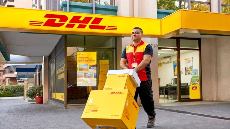 dhl express employee in bahrain leaving with a trolley of parcels