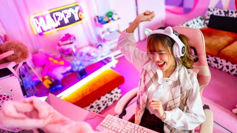 Young Asian woman esport player playing online game on computer in bedroom. Attractive girl vlogger influencer gamer enjoy and fun live streaming broadcast games challenge on social media platform.