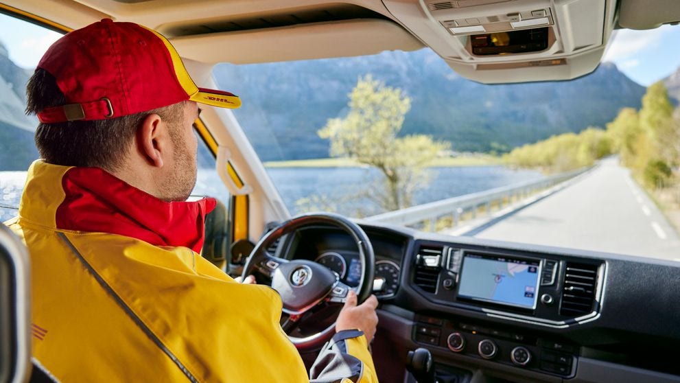 male dhl employee driving a delivery van in a rural area