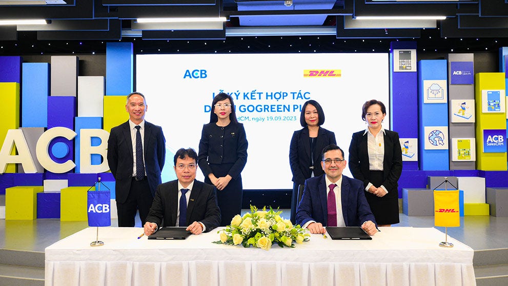 acb bank in vietnam and dhl express representatives co-signing an agreement to reduce scope 3 emissions