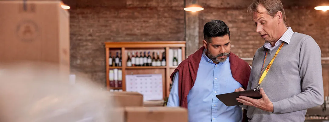 Hombre mostrando a otro hombre algo en una tablilla