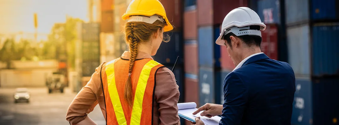 man and woman in hard hearts looking at clipboard