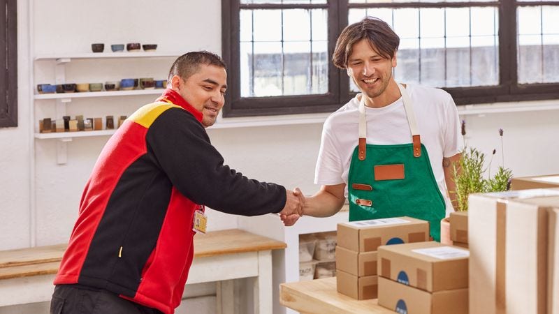 store owner and dhl express employee shaking hands while looking at packages on a table