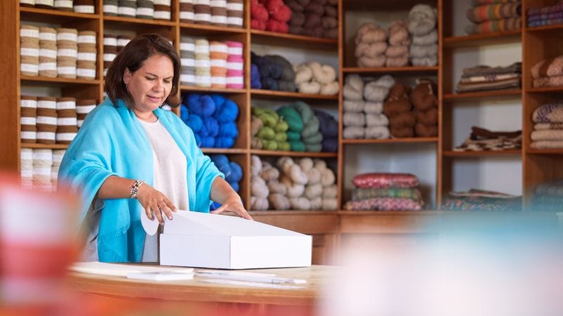 Female wool shop owner choosing the right DHL shipping box size for her parcel