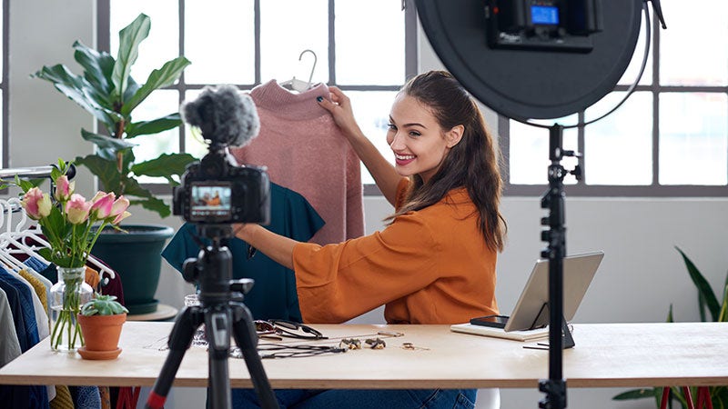 woman smiling at camera holding up a sweater