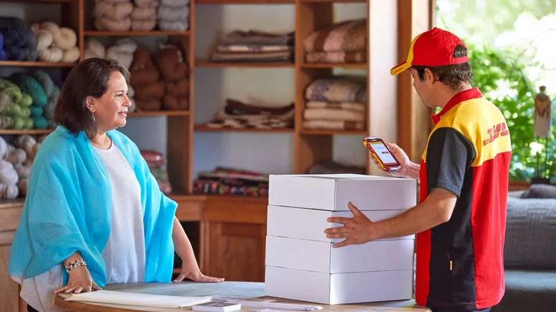 a dhl employee scanning parcels for pickup from a wool shop owner