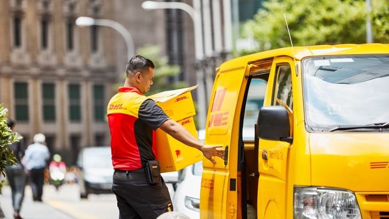 DHL parcel carrier next to his car.