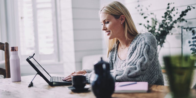 Woman sitting at desk with laptop, tea and water bottle