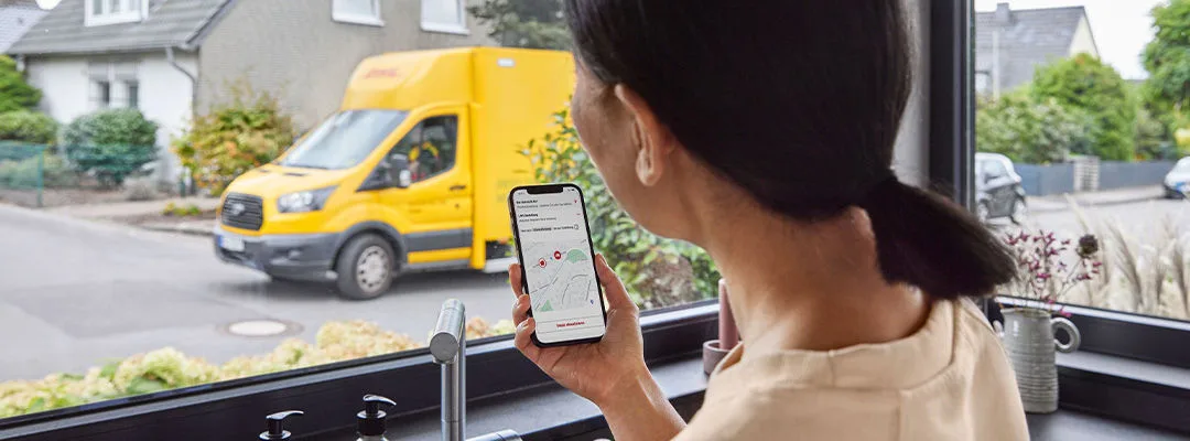 woman looking at mobile phone screen with DHL van in window