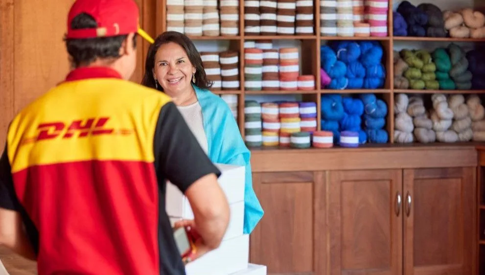 Older woman shop owner handing her packages to DHL courier