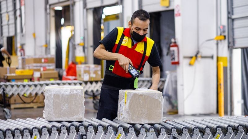  DHL Express employee using a smart scanner to manage shipments at a logistics distribution center