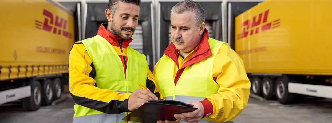 two men in a DHL car  park looking at clipboard