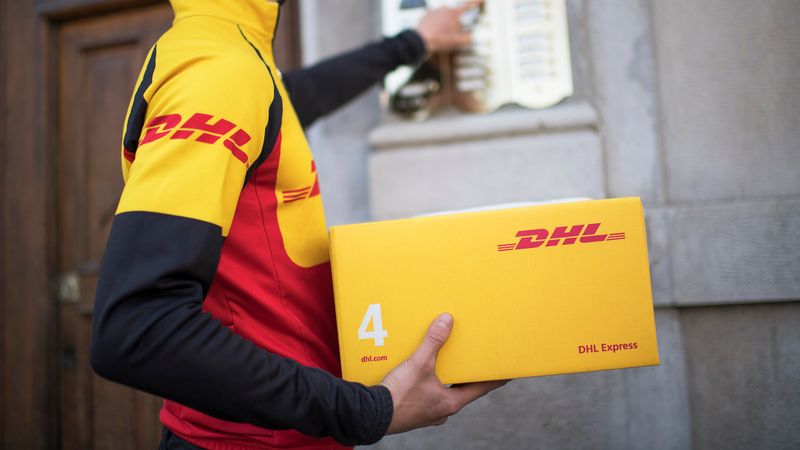 Male DHL employee in Thailand ringing a doorbell while holding a DHL package