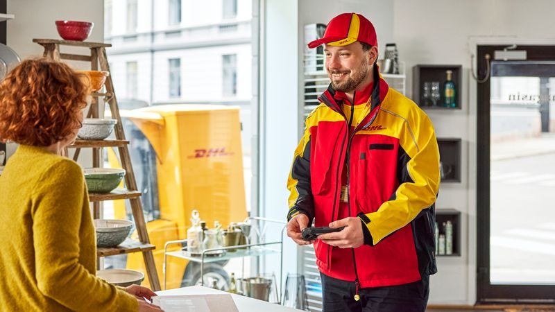 A male DHL employee is delivering a parcel to a female customer in her livestreaming shop.