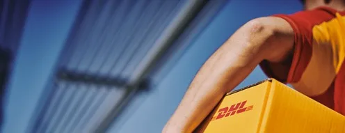A DHL courier confidently carries a branded yellow package across a modern bridge, symbolizing speed, reliability, and global logistics connectivity. The image conveys professionalism and efficient service in parcel delivery.