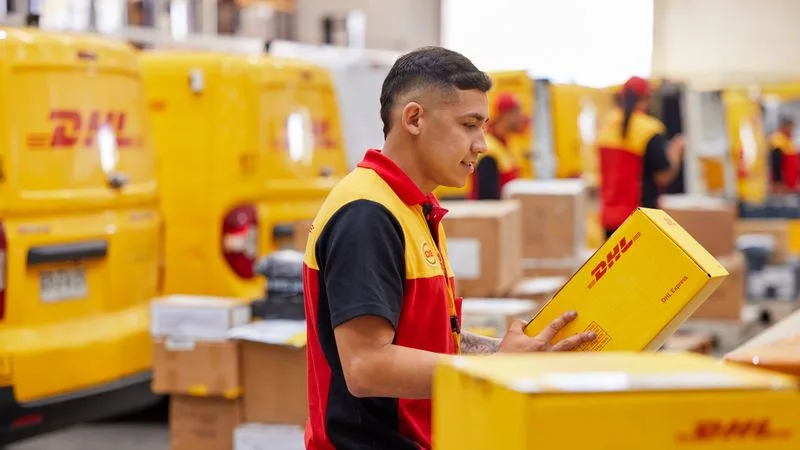 A happy DHL employee inspecting a package for cross-border trade