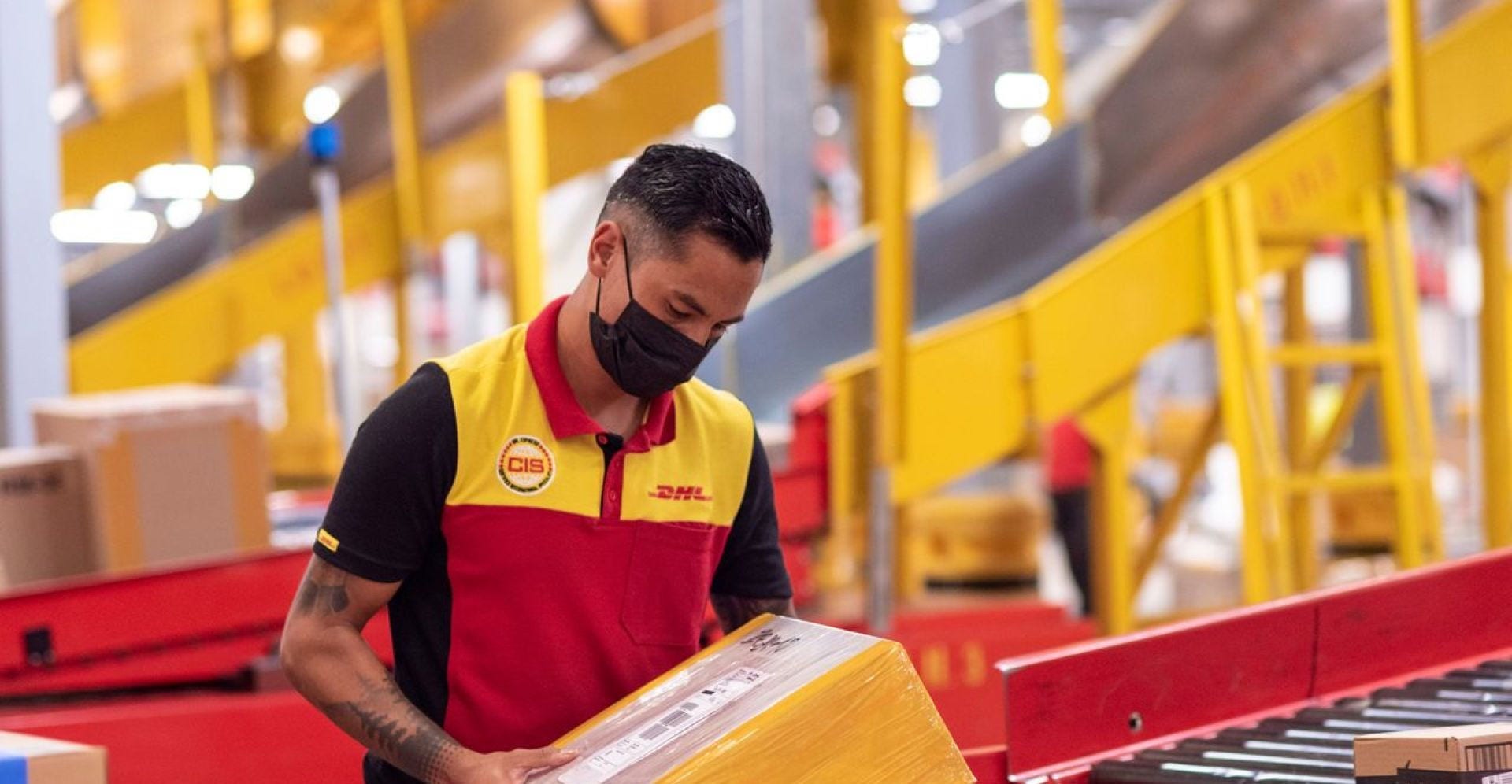 dhl employee checking packages on the conveyor belt