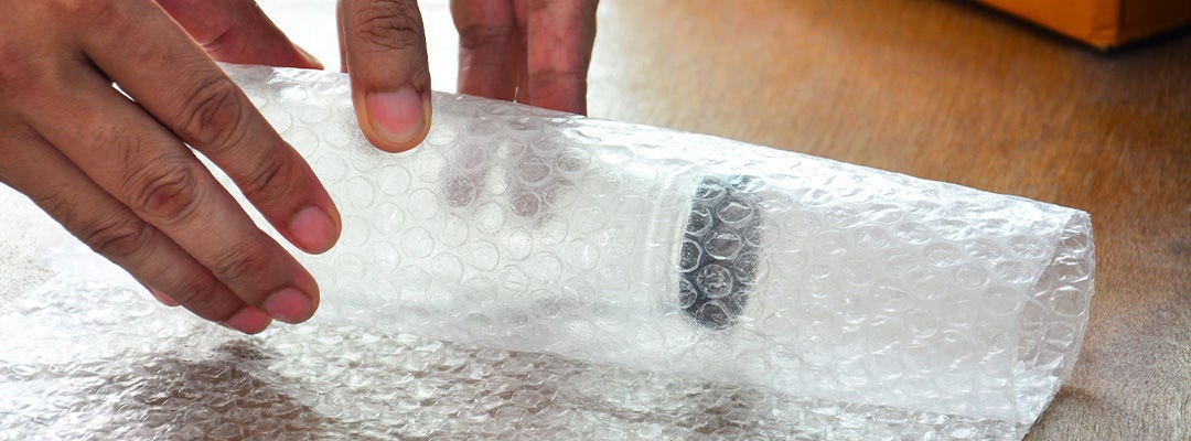 man wrapping bottle in bubble wrap