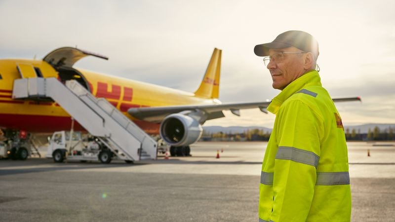 a dhl employee supervising a dhl plane ready from international shipping from malaysia