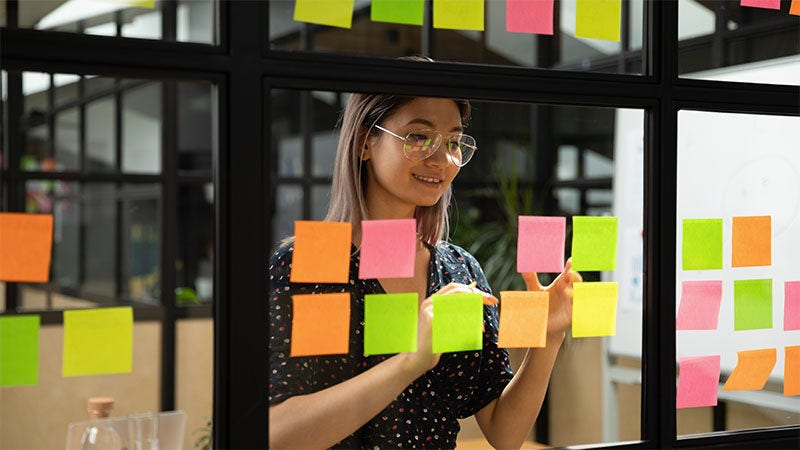 femme posant des post-it sur une fenêtre