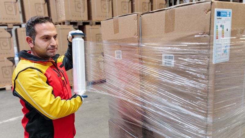 dhl express employee wrapping a shipment of heavy items for shipping