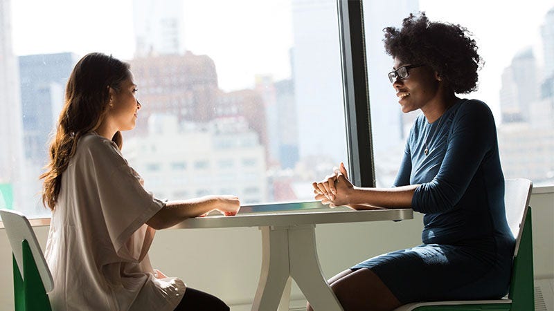 two women sitting and smiling at each other