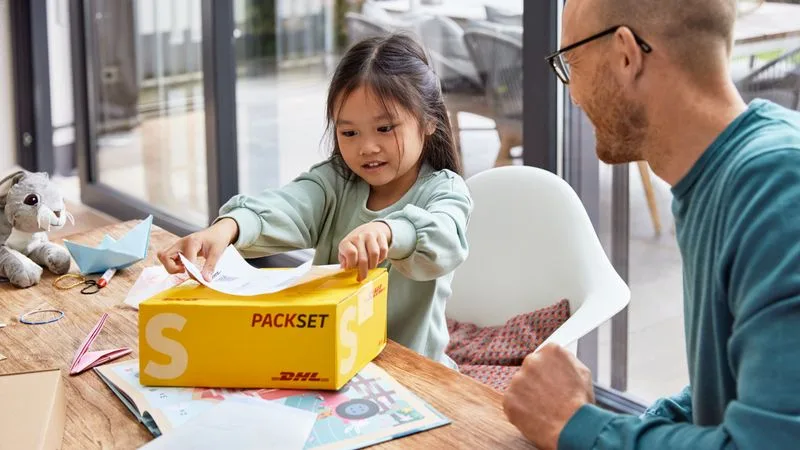 little girl attaches packing list on parcel for shipping