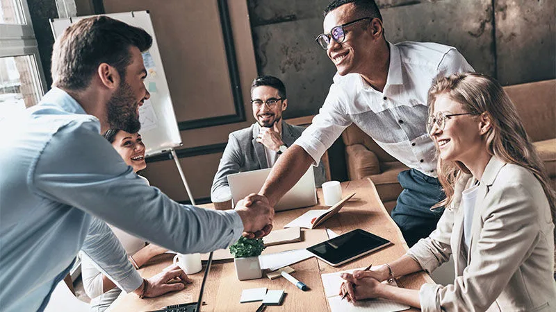 two men shaking hands over a table