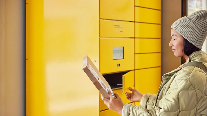 a woman taking a package from a parcel locker, one of the logistics solutions from dhl