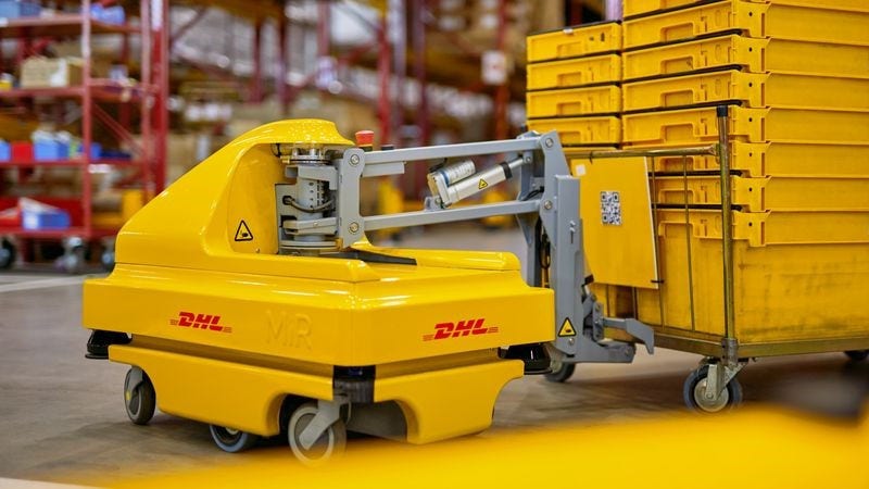 a dhl robot pulling a cart in a storage hub