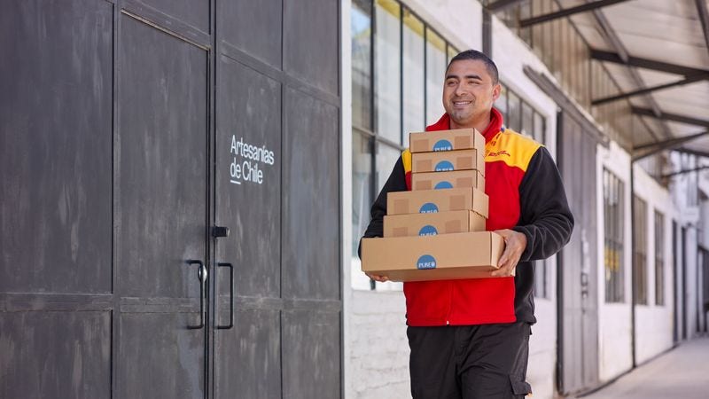 A male DHL employee is carrying parcels from pickup