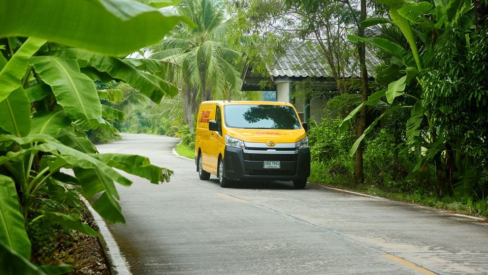 DHL van driving on road surrounded by trees