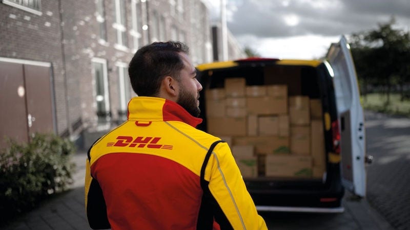 dhl express delivery driver loading up a packed van full of deliveries