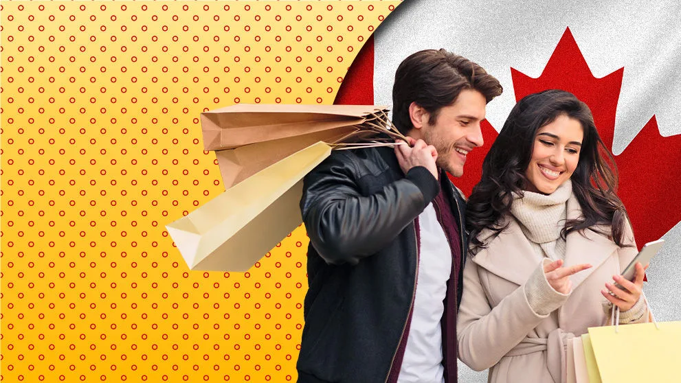 Millenial man and woman smiling, with shopping bags looking at phone