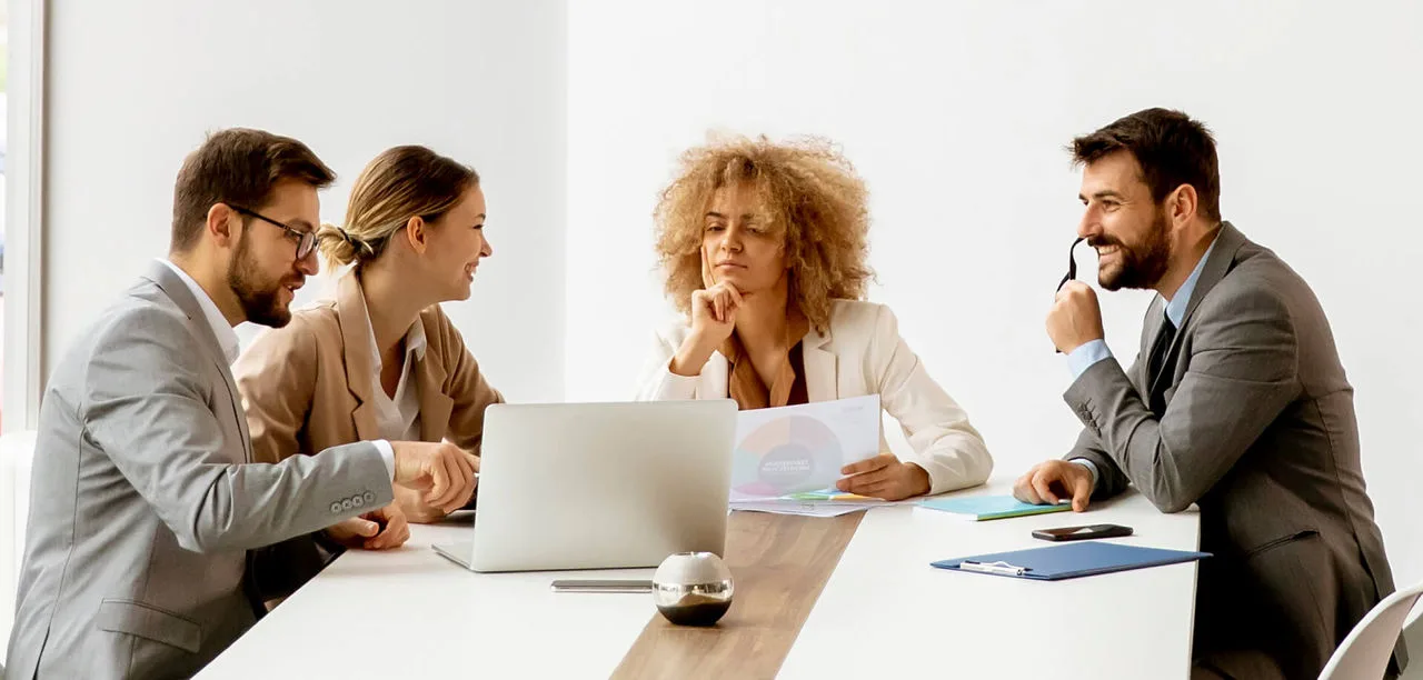 employees reviewing laptop screen and papers